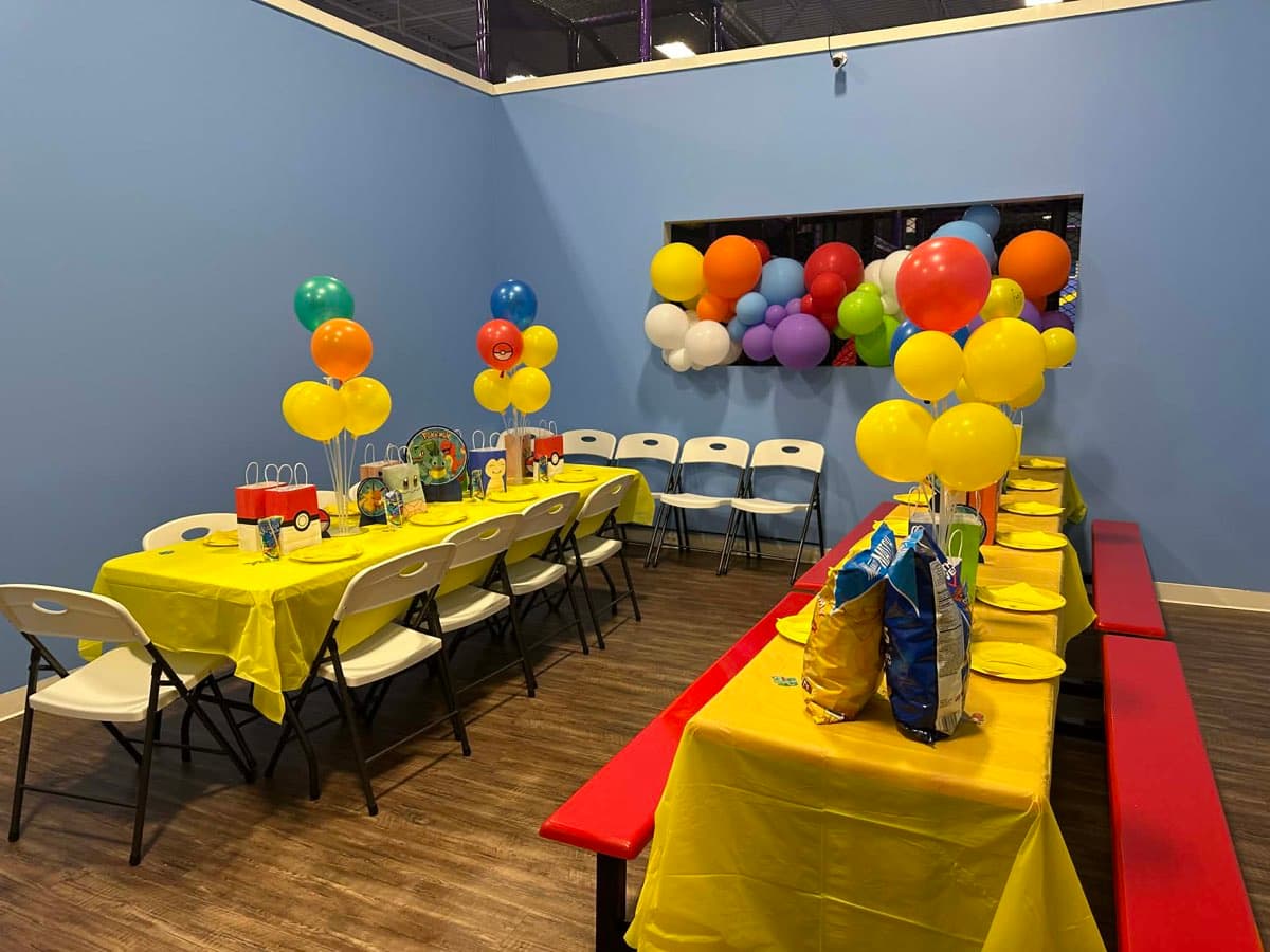 Party room with colorful balloons and yellow tablecloths at Sheffield Village